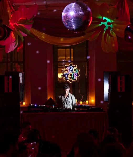 The DJ booth under a disco ball and the Discoteca neon